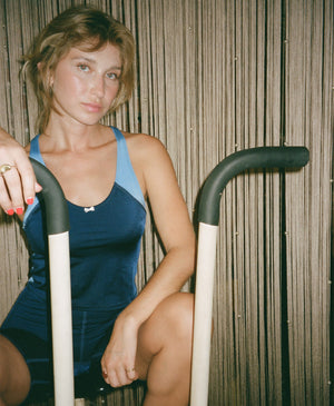 Wear One's At High Jump Tank in navy and sky blue on model sitting on elliptical