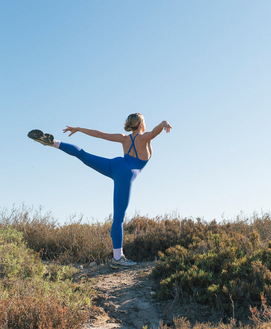 Wear One's At Liberty Unitard in royal Blue on model kicking backwards pose