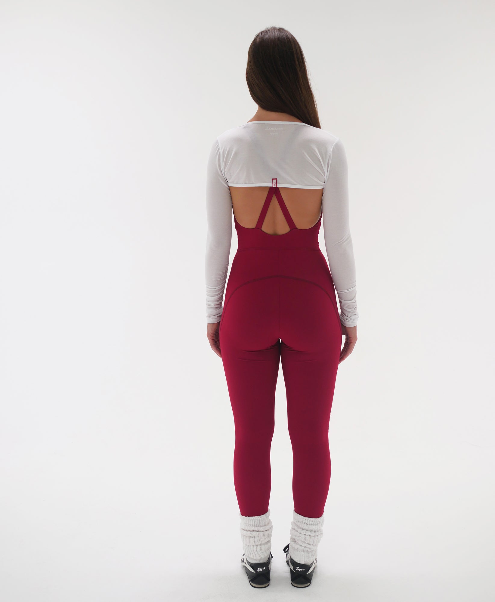 Wear One's at Liberty Unitard in tango red on model wearing a white shrug back view