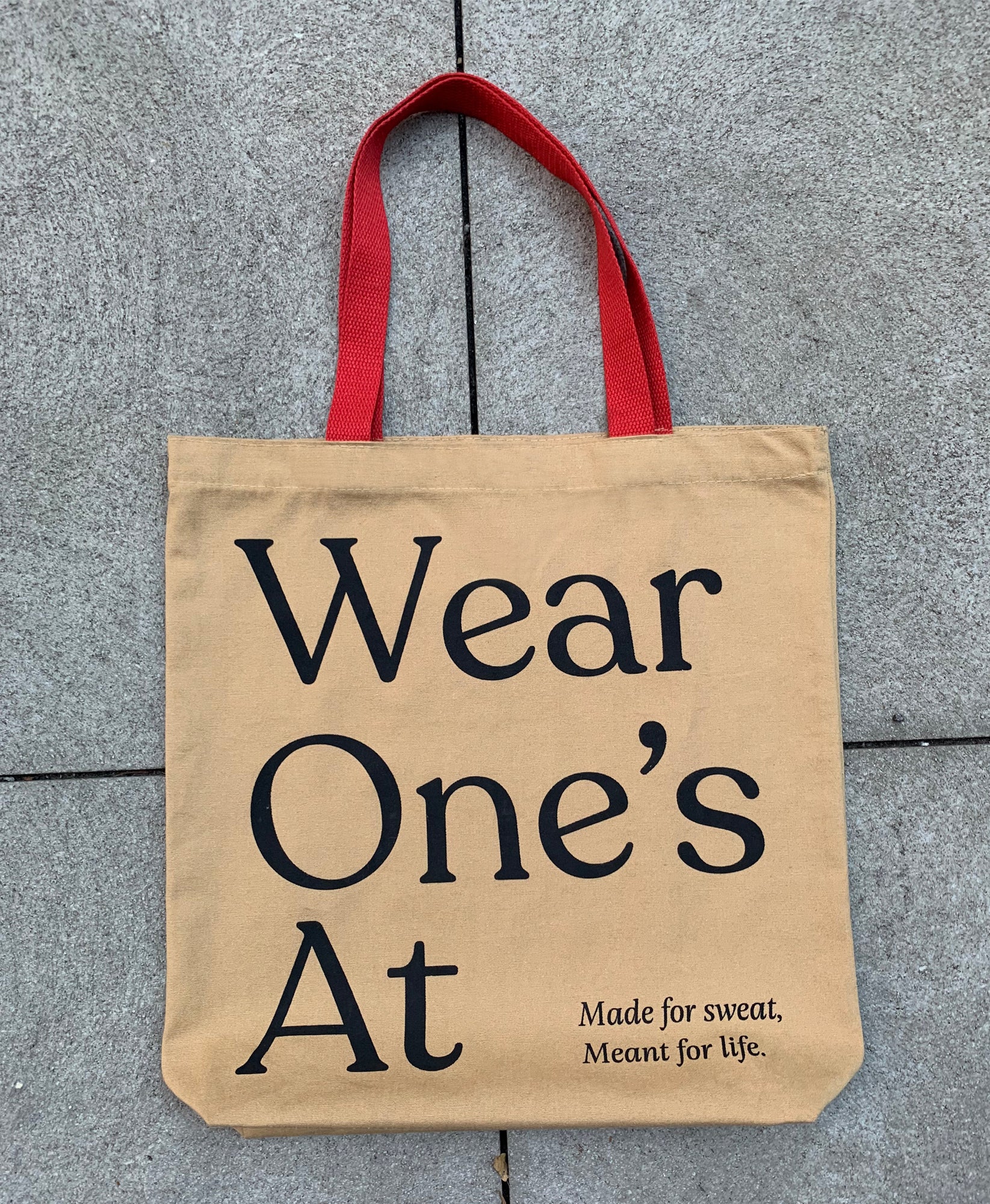 Wear One's At Tote with red handles laying on the ground