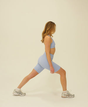 Wear One's At Tech Wave Bike Shorts in In Your Dreams Light Blue on Model Lunging Side View
